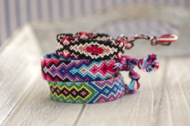 Ahşap arka plan, gökkuşağı renkleri, damalı desen üzerinde dostluk üç renkli el yapımı doğal dokuma bilezik