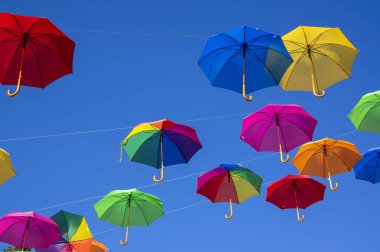 Mavi arka planda izole edilmiş bir halat üzerinde asılı bir grup şemsiye, duvar kağıdı arka plan, parlak çeşitli renkler