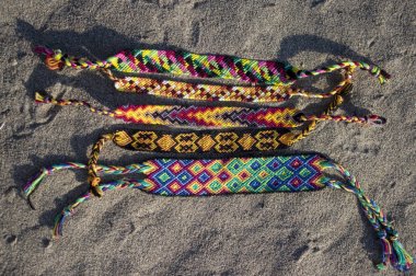Kum arka plan, gökkuşağı renkleri, damalı desen dostluk renkli el yapımı ev yapımı doğal dokuma bilezik Grubu