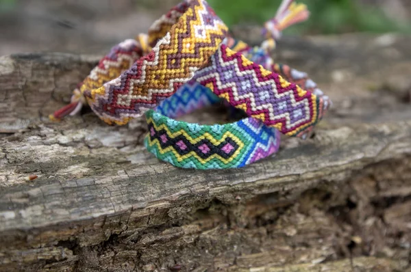 Grupo de coloridos hechos a mano pulseras tejidas naturales de amistad sobre fondo de madera vieja, patrones a cuadros — Foto de Stock