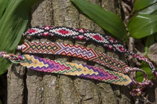Grupo de coloridos hechos a mano pulseras tejidas naturales de amistad sobre fondo de madera vieja, patrones a cuadros — Foto de Stock