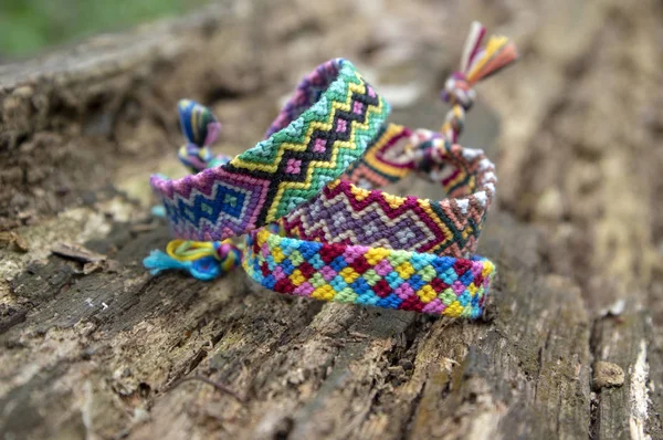 Eski ahşap arka plan üzerinde dostluk renkli el yapımı ev yapımı doğal dokuma bilezik grubu, damalı desenler