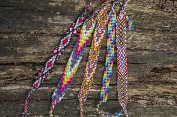 Groupe de bracelets tissés naturels faits à la main colorés d'amitié sur fond de vieux bois, motifs à carreaux — Photo