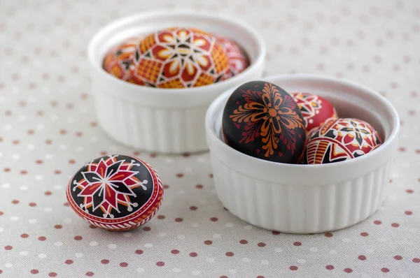 Coloridos huevos de Pascua pintados en cuencos blancos en mantel punteado, tradicional hermosa naturaleza muerta de Pascua — Foto de Stock