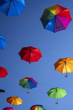 Mavi arka planda izole edilmiş bir halat üzerinde asılı bir grup şemsiye, duvar kağıdı arka plan, parlak çeşitli renkler