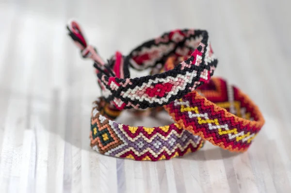 Tres pulseras tejidas naturales coloridas hechas a mano hechas a mano de la amistad aisladas en fondo de madera claro — Foto de Stock