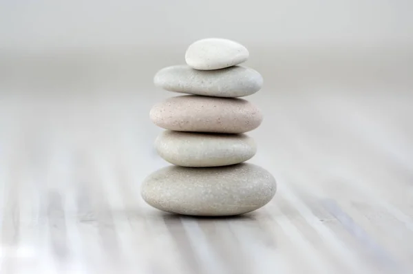 Armonía y equilibrio, cairns, simples piedras aplomo sobre fondo gris claro de madera, simplicidad escultura zen roca —  Fotos de Stock