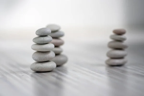 Armonía y equilibrio, tres cairns, guijarros aplomo simples sobre fondo gris claro de madera, simplicidad escultura zen roca — Foto de Stock
