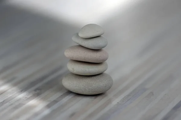 Armonía y equilibrio, cairns, guijarros aplomo simples sobre fondo gris claro de madera, simplicidad escultura zen roca —  Fotos de Stock