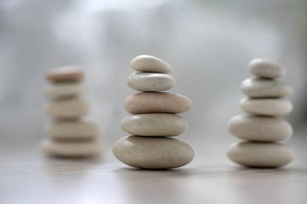 Harmony and balance, three cairns, simple poise pebbles on wooden light white gray background, simplicity rock zen sculpture