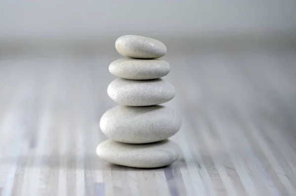 Armonía y equilibrio, cairns, guijarros aplomo simples sobre fondo gris claro de madera, simplicidad escultura zen roca —  Fotos de Stock