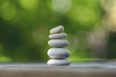 Uyum ve denge, cairns, ahşap masa üzerinde basit duruş çakıl, doğal yeşil arka plan, basit kaya zen heykel