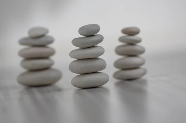 Harmony and balance, three cairns, simple poise pebbles on wooden light white gray background, simplicity rock zen sculpture