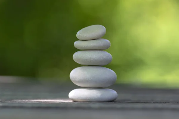 Harmony and balance, cairns, simple poise pebbles on wooden table, natural green background, simplicity rock zen sculpture