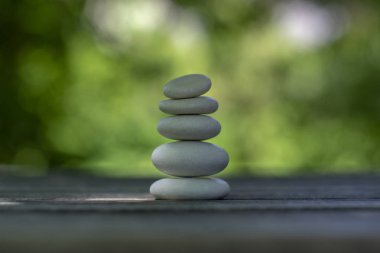 Uyum ve denge, cairns, ahşap masa üzerinde basit duruş çakıl, doğal yeşil arka plan, basit kaya zen heykel