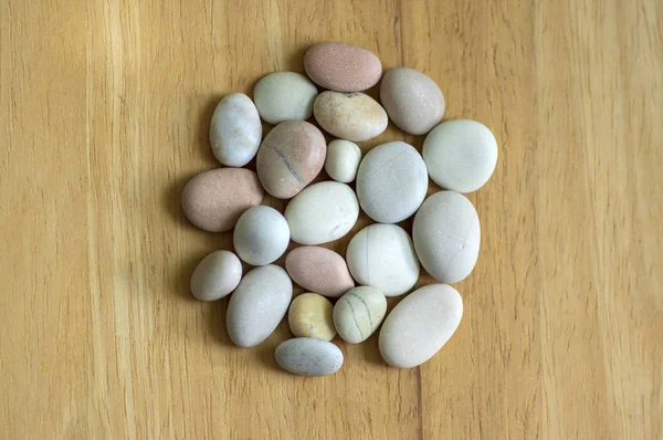 Gruppo di pietre bianche, grigie e marrone chiaro su fondo di legno, spiaggia di ciottoli, cerchio a forma di mandala — Foto Stock