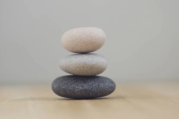 Harmonia e equilíbrio, cairns, seixos simples em madeira luz fundo cinza branco, simplicidade escultura zen rocha — Fotografia de Stock
