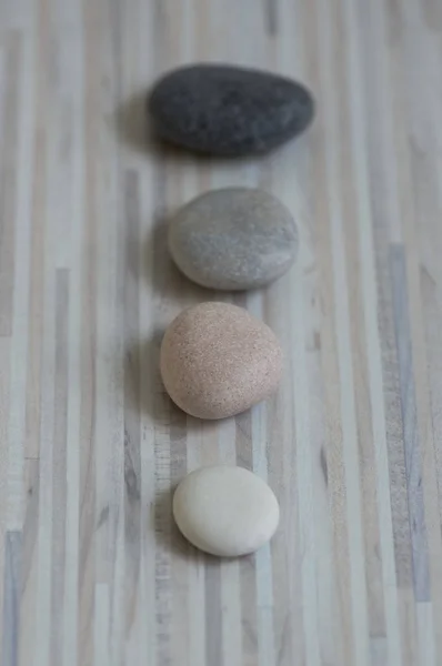 Fila de piedras zen grises en estera de madera, cinco guijarros en una fila, guijarros de masaje, baja profundidad de campo — Foto de Stock