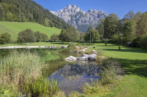 Veřejné biotopové jezero ve Verfenwengu obklopené Alpami, nádherné skály v odrazu vodní hladiny, úžasná zeleň — Stock fotografie