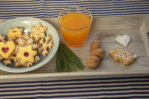 Christmas breakfast on wooden tray, fresh orange juice gingergread, shortcrust pastry cookies and pour feliciter pig 2020