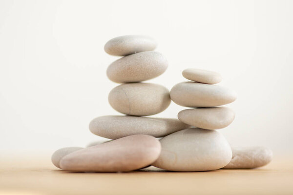 Simplicity stones cairns isolated on white background, group of light gray pebbles built in towers, wooden table, harmony and balance