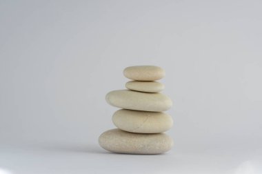 Bir basitlik taşı beyaz arka planda izole edilmiş, kulede beş beyaz çakıl taşı grubu, uyum ve denge.