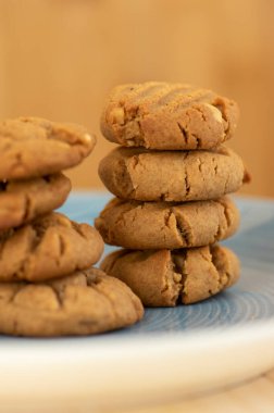 Bambu açık kahverengi tahta üzerinde çok lezzetli fıstık ezmeli bisküviler, altın fırında sağlıklı, mavi tabakta iki kulede inşa edilmiş.