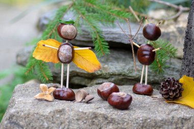 Melek ve şeytan figürleri sonbahar bahçesinde kestane, güvenlik kibritleri ve kuru yapraklardan yapılmıştır.