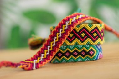 Üç el yapımı renkli doğal örgü bilezik açık ahşap arka planda izole edilmiş, gökkuşağı renkleri renkli, yeşil arkaplan