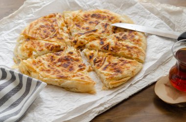 Türk çayı yanındaki masada peynir pasta dilimlenmiş.