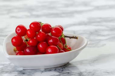 Mermer zemin üzerine beyaz tabakta taze kiraz.