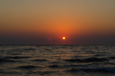 Denizin üzerinde gün batımı. Güneşin parlaklığı denize vuruyor..