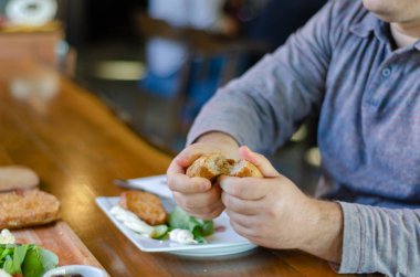 Adam elinde kahvaltıda ekmek alır. O kahvaltı için eliyle ekmek bölünmüş.