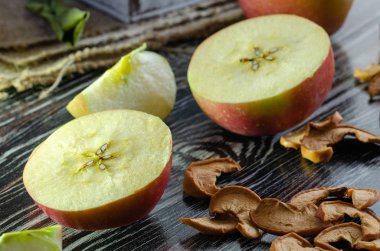 Lezzetli taze kırmızı elma ve kurutulmuş elma dilim üzerinde ahşap masa vardır.