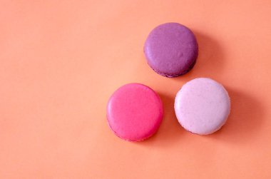 Renkli macaroons üstten görünüm, turuncu arka plan vardır.