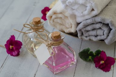 Havlu ve beyaz arka plan üzerinde üstten görünüm, izole şişeler güzel çiçeklerle yakın çekim