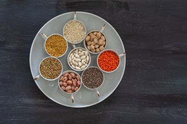 Vegan protein kaynağı. Baklagiller - mercimek, nohut, fasulye, İç bakla, bulgur, chia tohum siyah arka plan üzerine. Üstten görünüm kopya alanı.