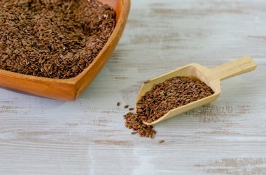 Ahşap kase ve bir kaşık keten tohumu veya keten tohumu. Beyaz arka plan üzerinde izole