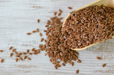 Tahta kaşık beyaz arka plan üzerinde kahverengi keten tohumu.