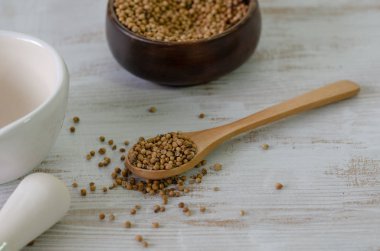 Tahta kaşık beyaz arka plan üzerinde yığın kişniş tohumu