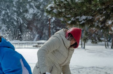 Genç kız ve annesi kartopu ormanda kışın oynayan.