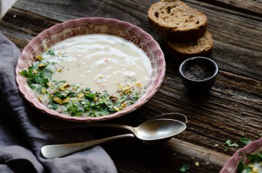 Kase sebze çorbası. Antep fıstığı vardır ve maydanoz çorbası üzerinde bırakır. Bu bir vintage pembe plaka üzerinde kahverengi ahşap bir masa mevcuttur. Üstten yatay üstten görünüm