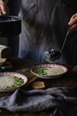 Kase sebze çorbası. Antep fıstığı vardır ve maydanoz çorbası üzerinde bırakır. Bu bir vintage pembe plaka üzerinde kahverengi ahşap bir masa mevcuttur. Üstten üstten görünüm