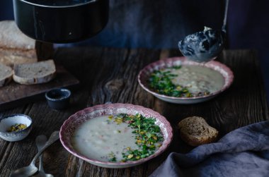 Kase sebze çorbası. Antep fıstığı vardır ve maydanoz çorbası üzerinde bırakır. Bu bir vintage pembe plaka üzerinde kahverengi ahşap bir masa mevcuttur. Üstten üstten görünüm