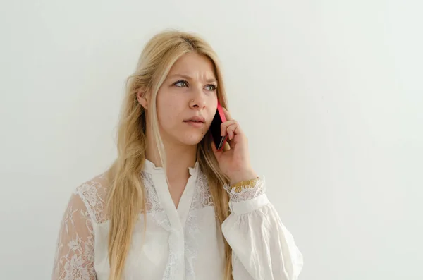 Blond meisje is praten over de telefoon en ze ziet er ongelukkig. — Stockfoto