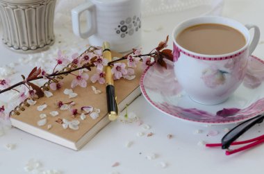 Bir defter, kalem, bahar dalı, bir fincan kahve ile Natürmort