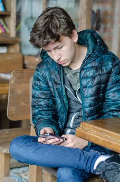 Adolescente menino está jogando com smartphone — Fotografia de Stock