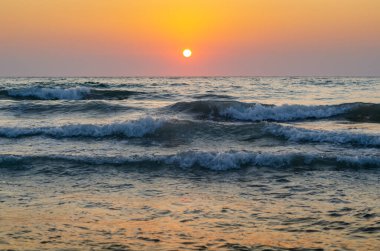 Denizin üzerinde gün batımı. Güneşin parlaklığı denize vuruyor..