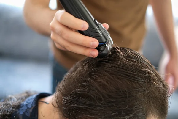 The young man is cutting  father\'s hair with hair clipper during coronavirus quarantine isolation at home .Home haircut concept.