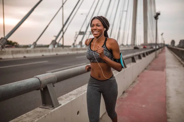 Young black woman is running in a city over a bridge